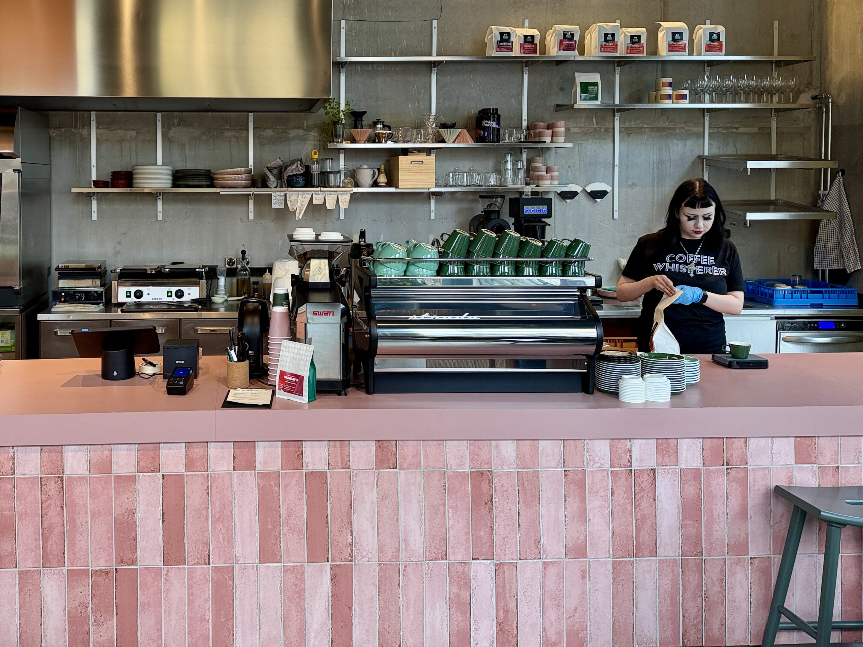 View of an espresso bar with a female barista behind the counter