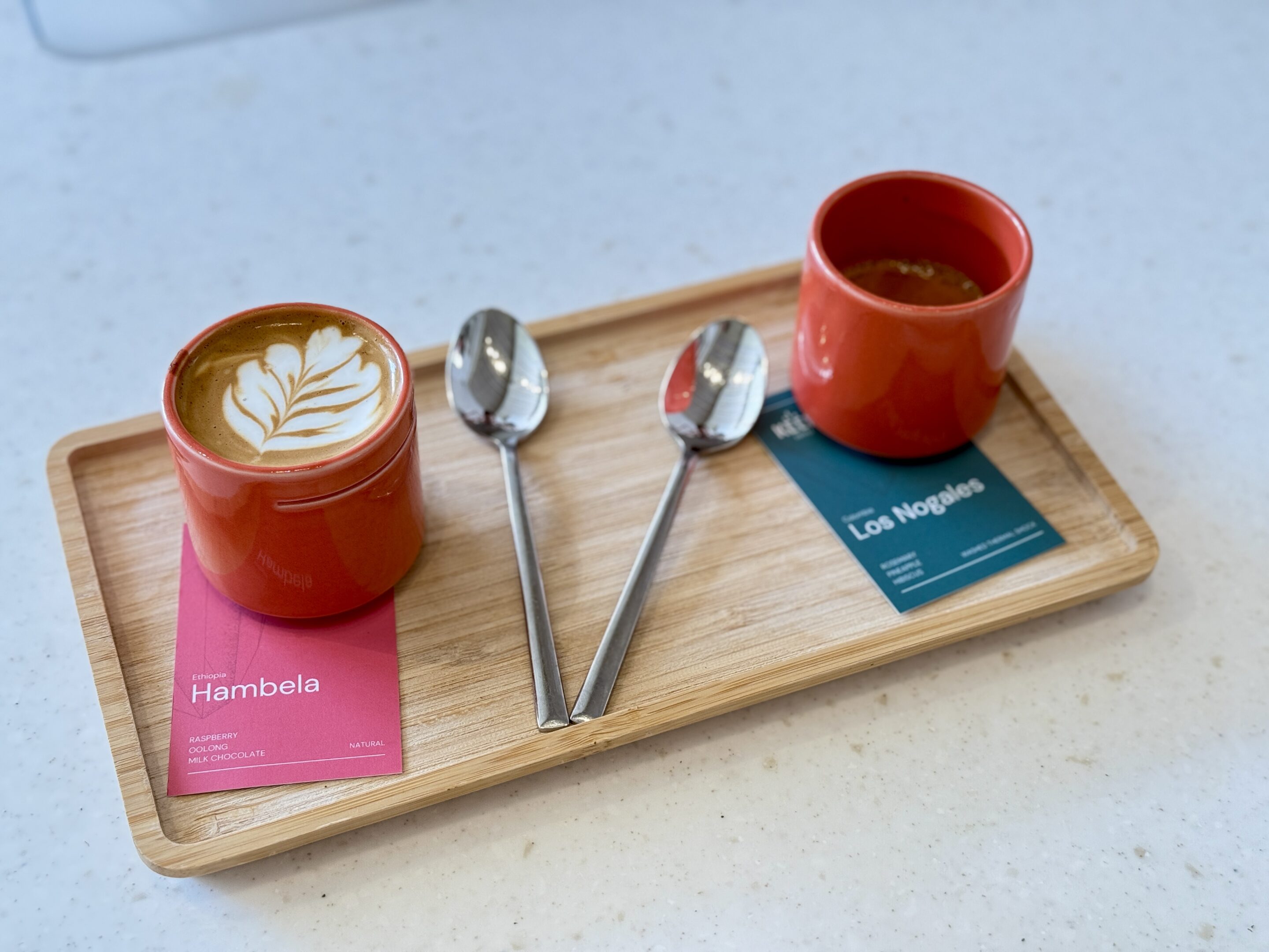 Two cups of coffee on a wooden tray.