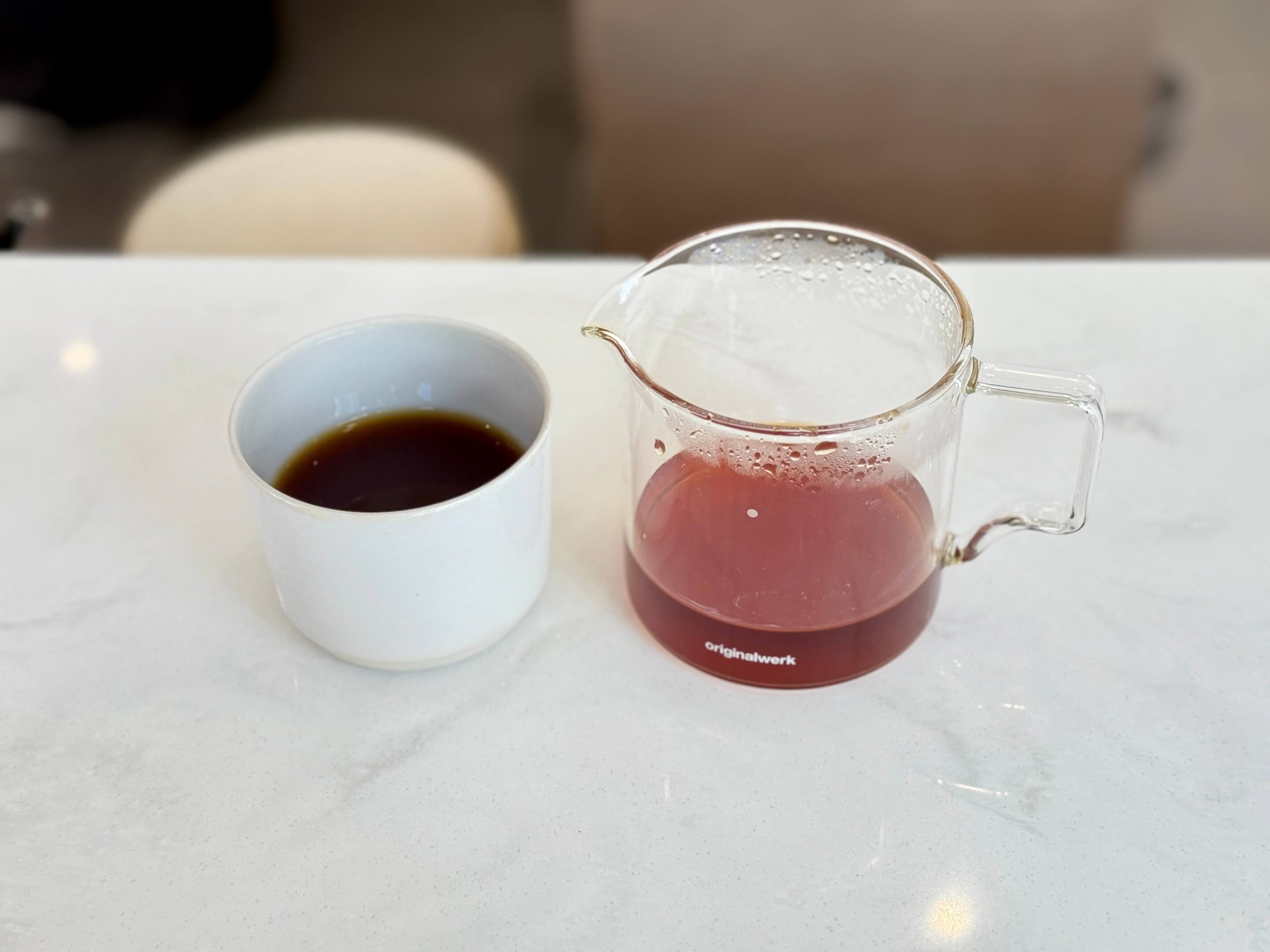 A cup of coffee with a small server also containing coffee