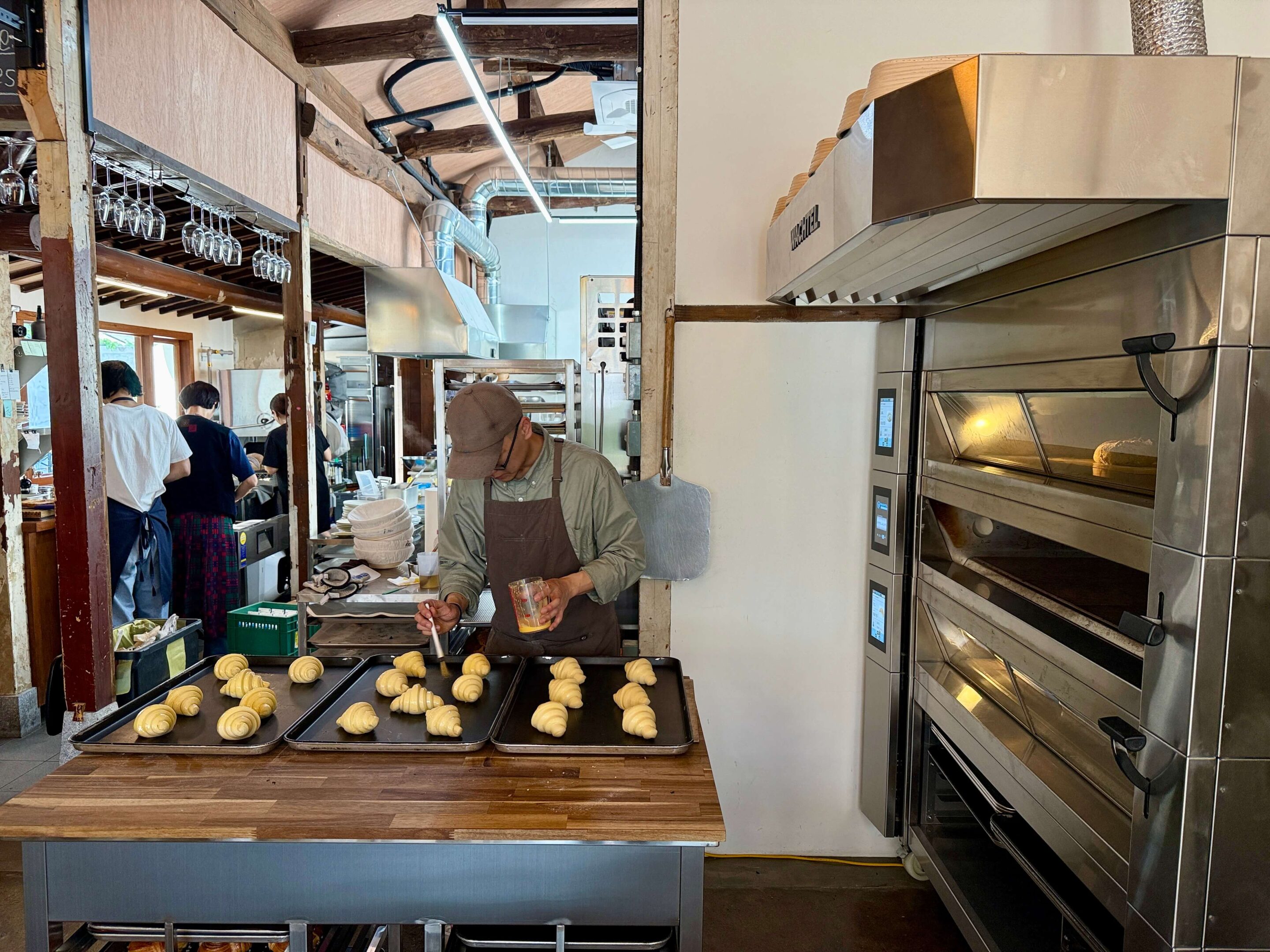 Patissery chef standing in front of a batch of croissants