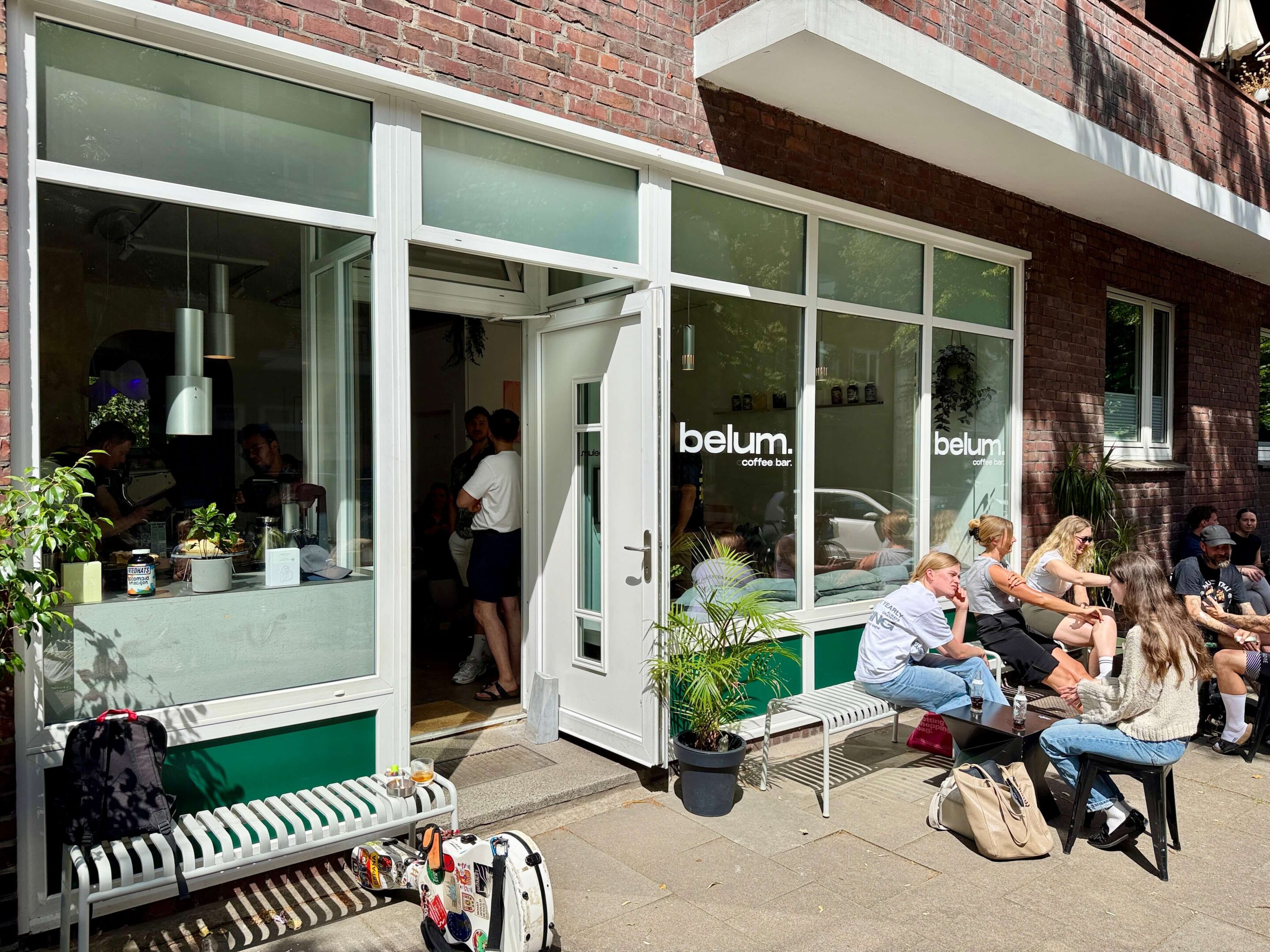 Outside view of a coffee bar with people sitting on a bench