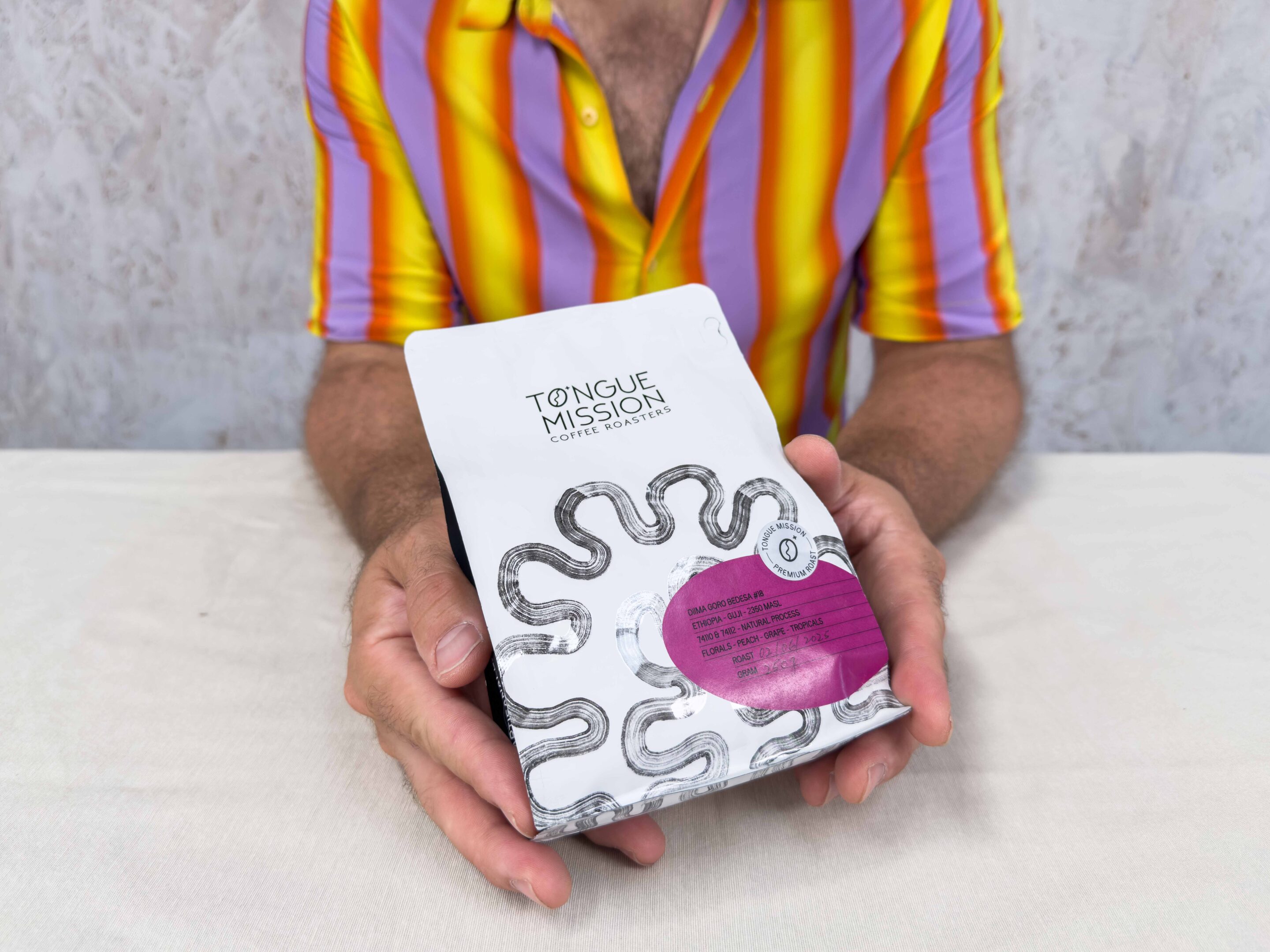 Coffee bag being held by person with colourful shirt
